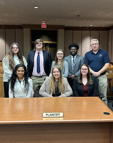 A group of Mock Trial students pose in a courtroom.