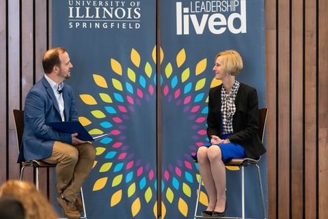 Two people site on chairs in front of UIS Leadership Lived banners