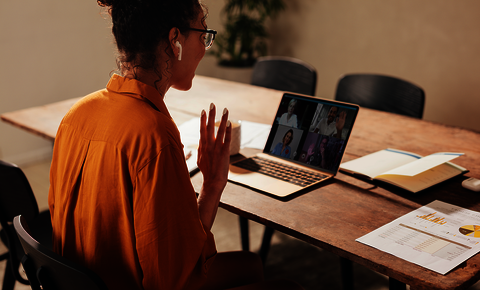 Profile of woman at computer in virtual meeting with many participants.