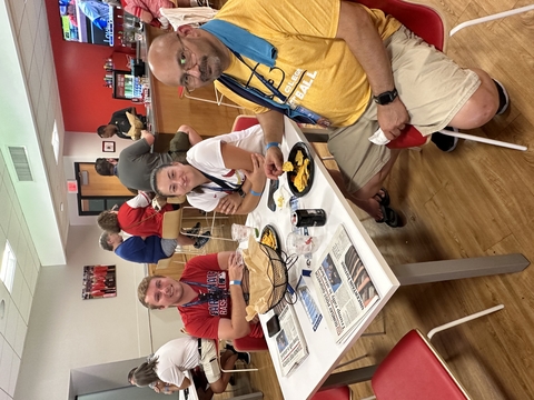 three people sit at a table while watching a St Louis Cardinals game