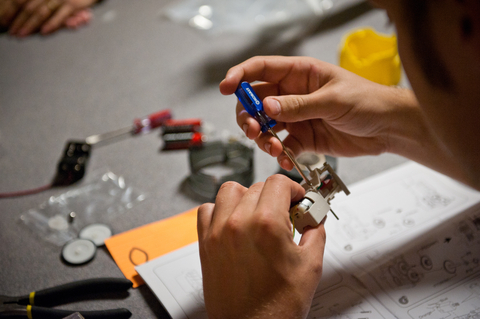 a person's hands working on a small device with a screwdriver