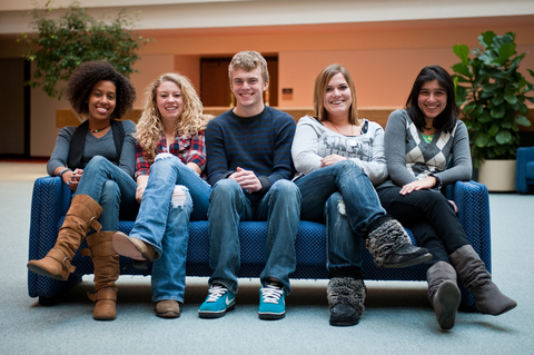 a group of five students sit on a couch