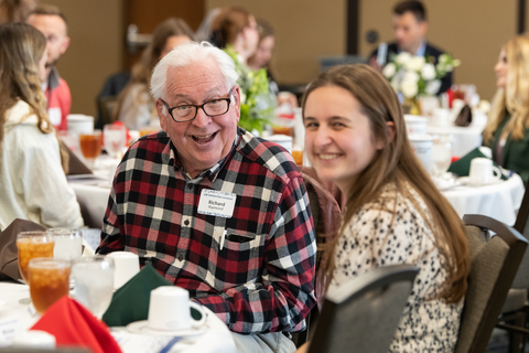 a donor and scholarship recipient smile for a photo while sitting at a table