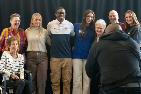 a group of students and donors pose for a photo being taken by a professional photographer