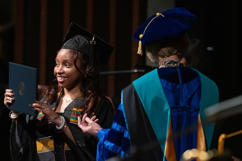 graduate holding up degree next to chancellor