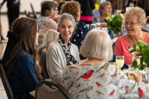 women smiling and chatting at a dining table.