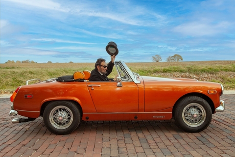 Abe Lincoln drives an orange convertible down a brick stretch of Route 66.