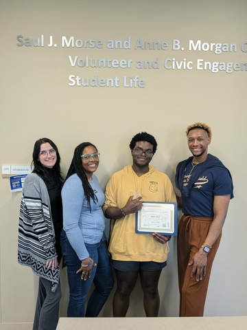 Deme Dees holding award with three professional staff members.