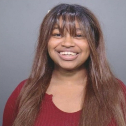 Student with long brown hair with a big smile and wearing a red sweater