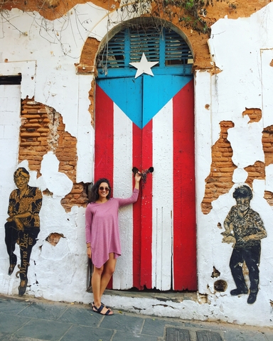 Female student posing in front of a door painted with the Puerto Rico flag