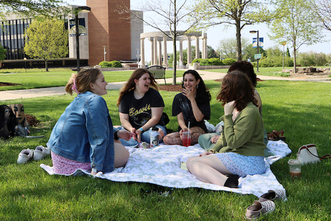 Four students have a picnic on the quad.