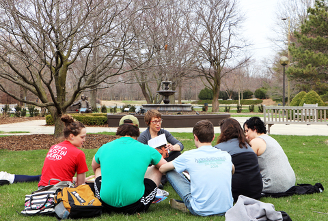 a group of students sitting on the grass of the Shakespeare Garden