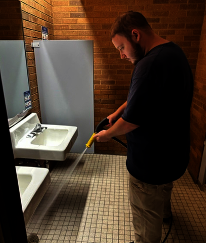 UIS Building Service Worker draining water through bathroom draining while cleaning