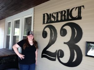 student posing next to District 23 signage