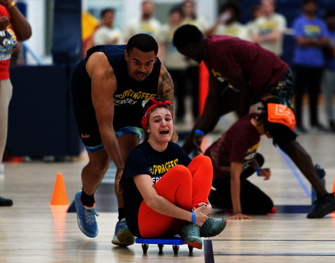 One student pushes another on a scooter board.