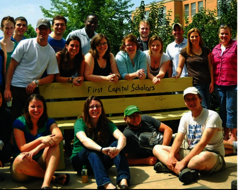 Students gathered around a bench that says "First Capital Scholars."