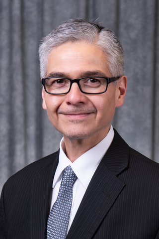 Head and shoulders photo of Dr. Jorge Villegas with suit and tie against gray background.