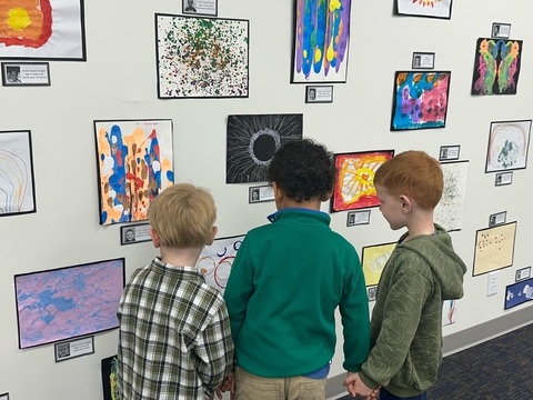 Children examine their artwork on the gallery wall