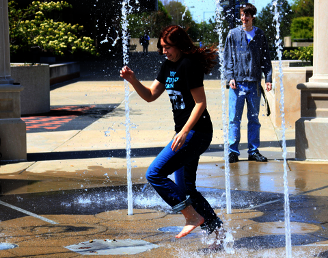 A student runs through the fountain of the Colonnade.