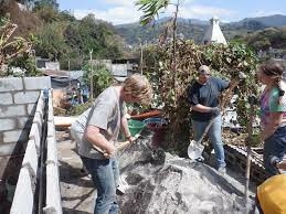 Three people outdoor mixing concrete to build a house