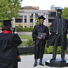 Grad taking photo next to Lincoln Statue
