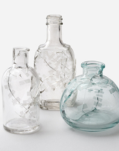  Three uniquely designed glass bottles displayed together, showcasing their distinct shapes and patterns.