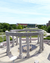Circular stone pavilion with columns in a park setting.