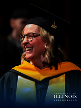 Graduate in cap and gown smiling at a ceremony.