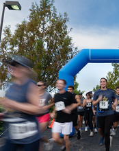Runners passing a blue inflatable arch, blurred motion.