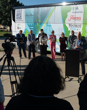People standing in front of a brightly colored bus, with camera setup in foreground.