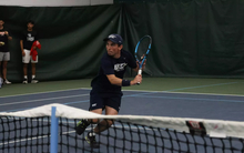 Pablo Herrera playing tennis in UIS blue in indoor facility