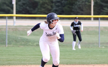 Rachel McMullen running the bases in white UIS softball uniform
