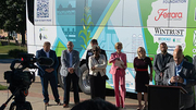 People standing in front of a brightly colored bus, with camera setup in foreground.