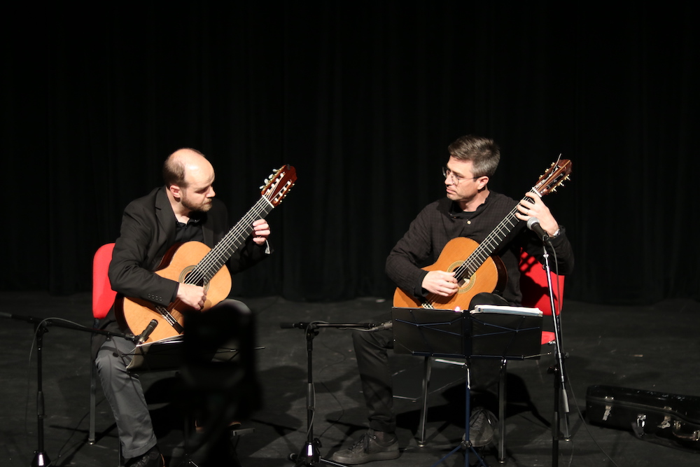 photo of two men on a stage playing guitars 