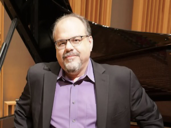 man standing next to a piano