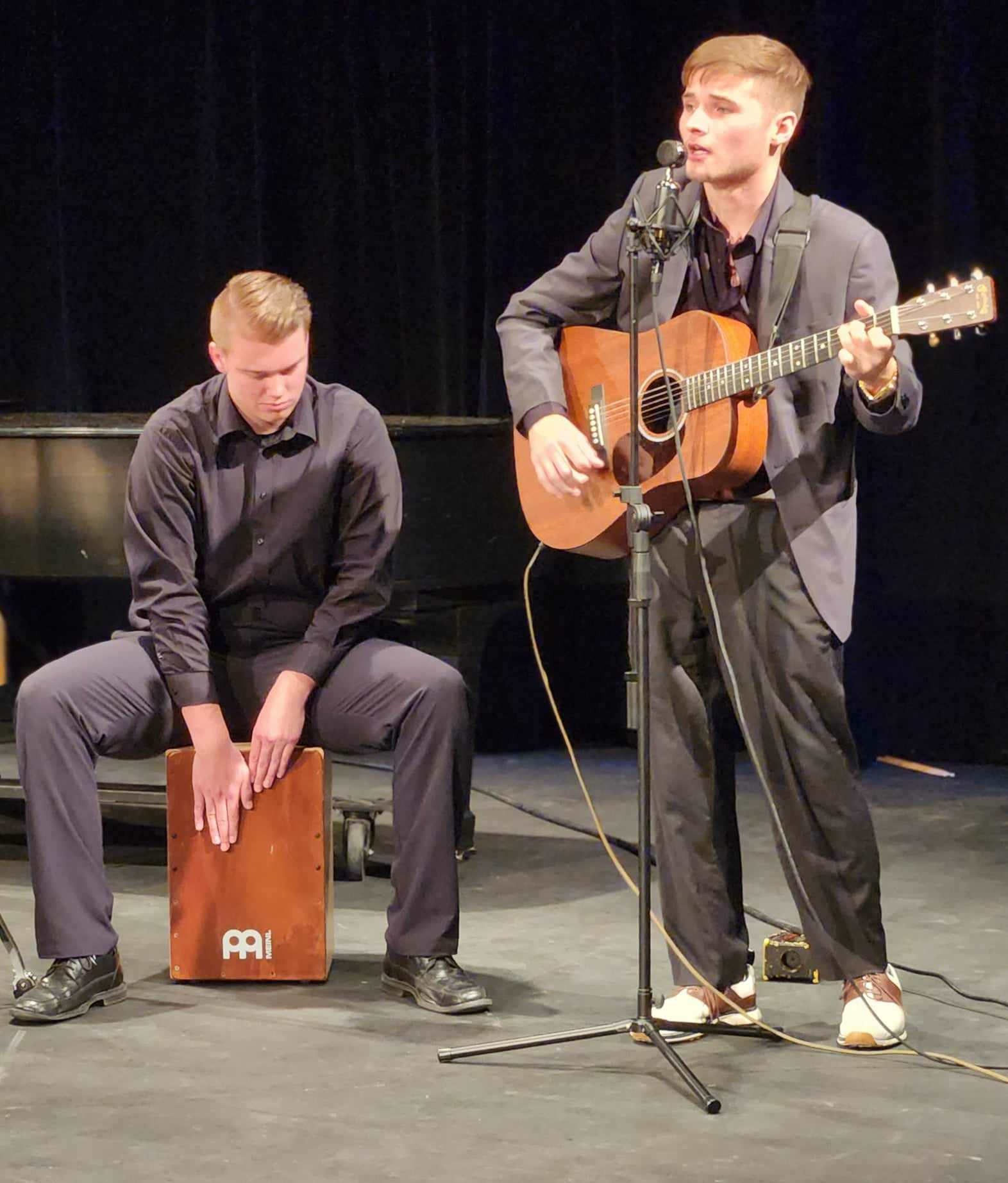 two guys playing the box drum and guitar