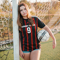 Rowan Severson holding a soccer ball and leaning on a goal 