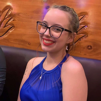 A headshot of Kiara Hobbs leaning against a wooden bench