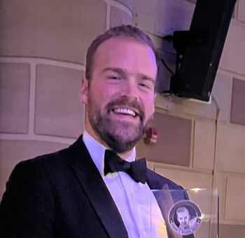 headshot of Luke Runyon holding an award