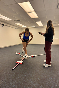 Two women in gym using Y balance equipment