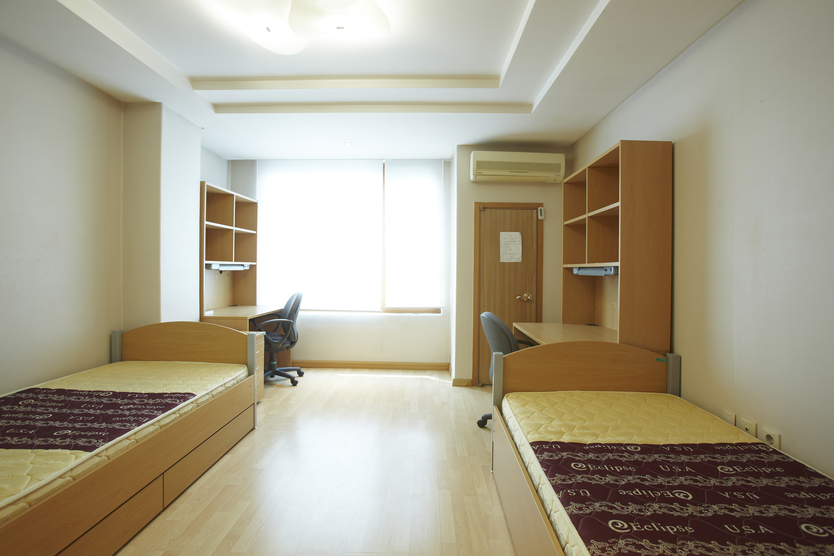 Example dorm room with two beds, two mattresses, two desks, two desk chairs and two wardrobes. 