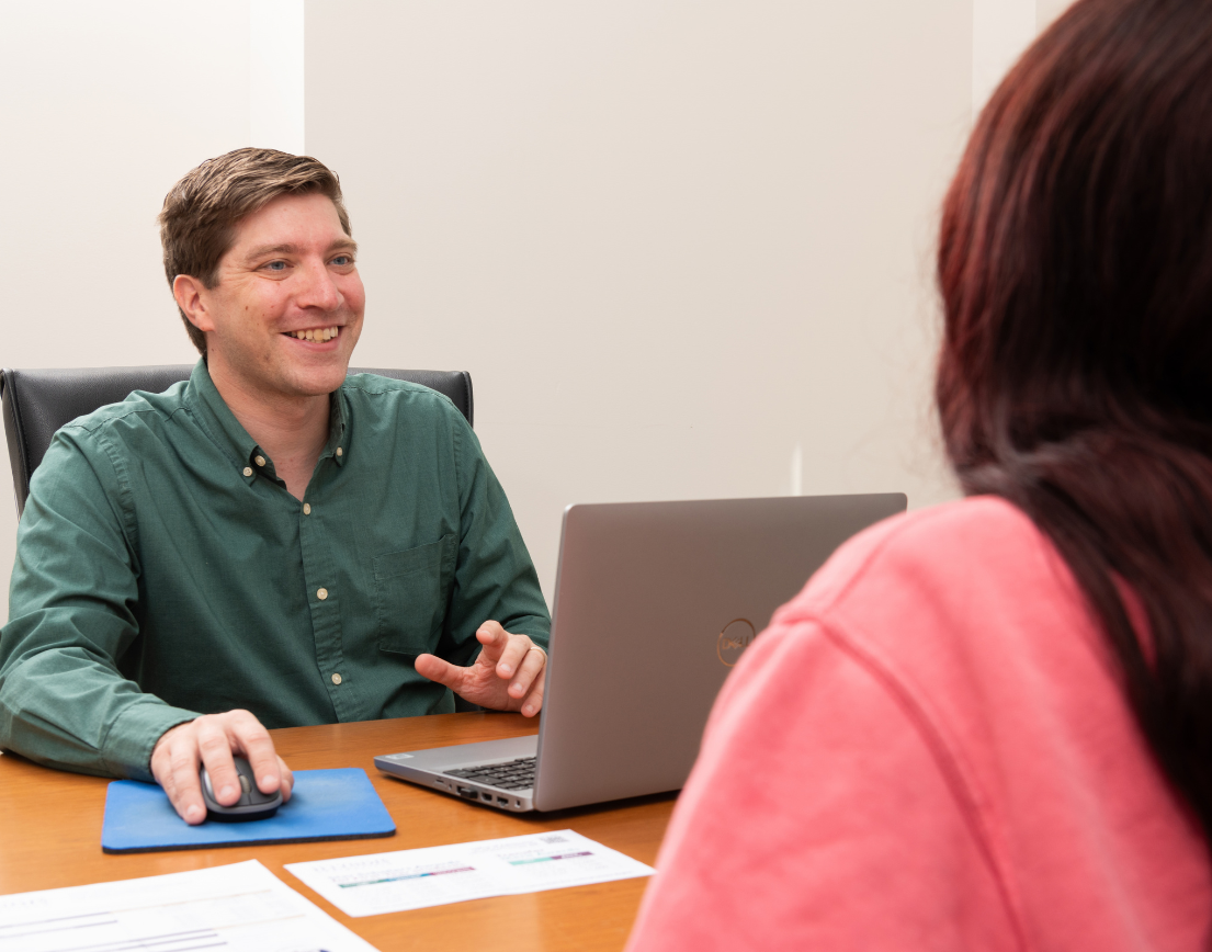 an adamic advisor smiling, speaking to a student 