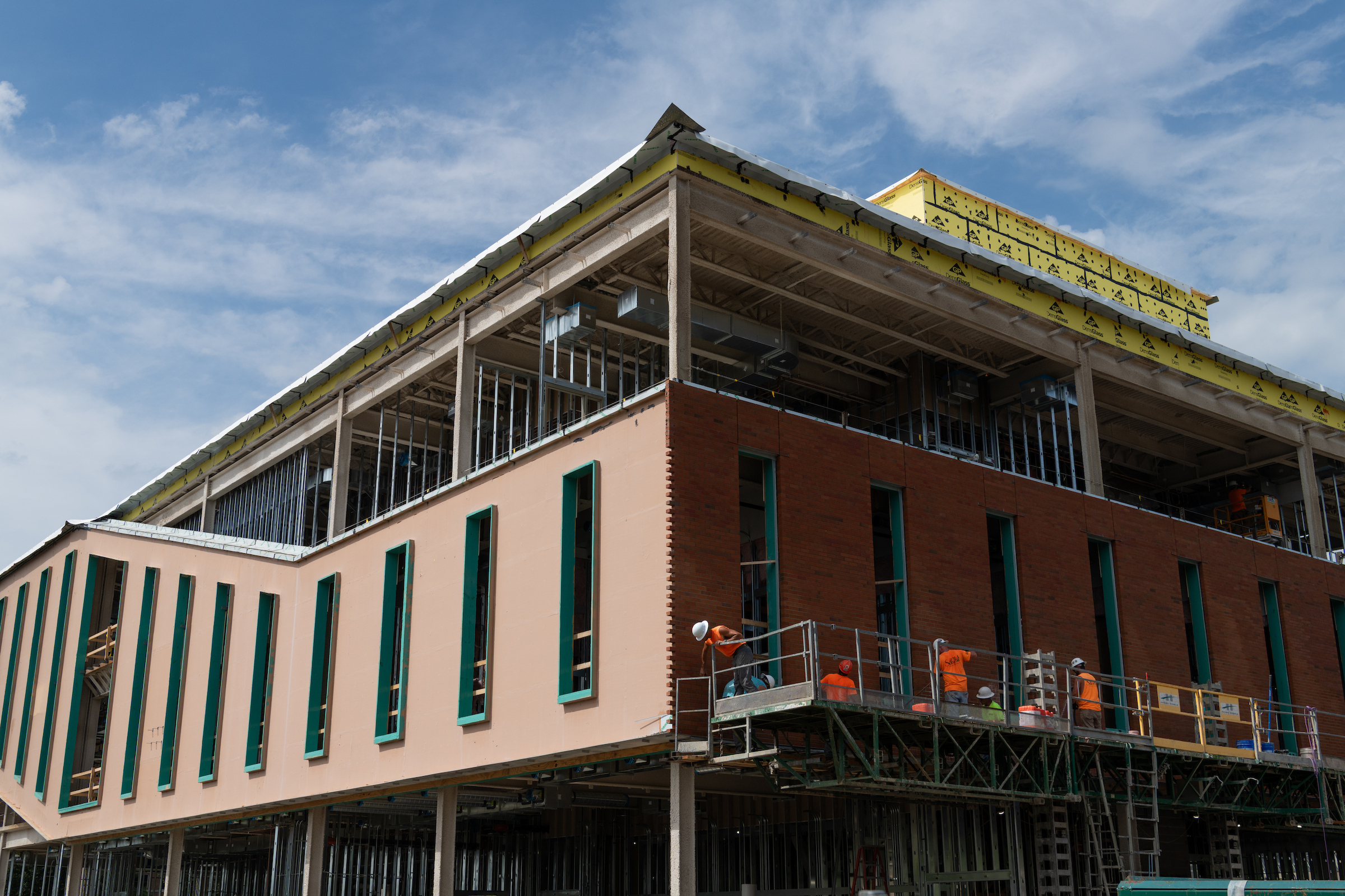 Construction workers on scaffolding install exterior brickwork on the UIS Library Commons building.