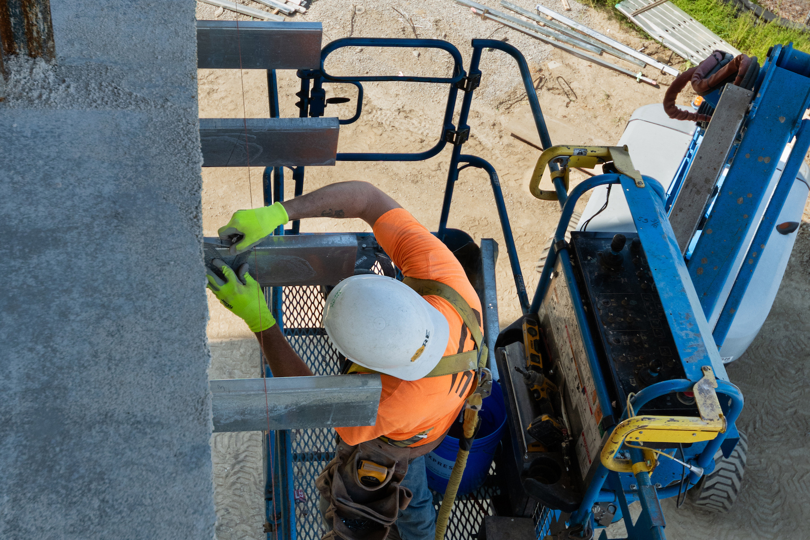 A construction worker on an elevated lift installs metal framing along an exterior wall of the UIS Library Commons.