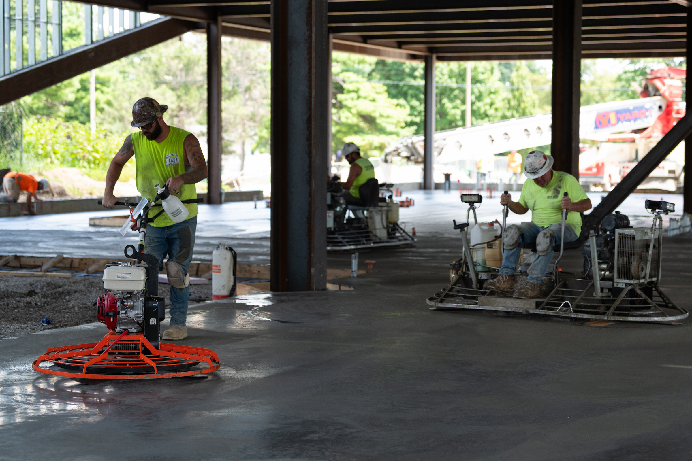 Construction workers use power trowels to smooth freshly poured concrete flooring inside the UIS Library Commons.
