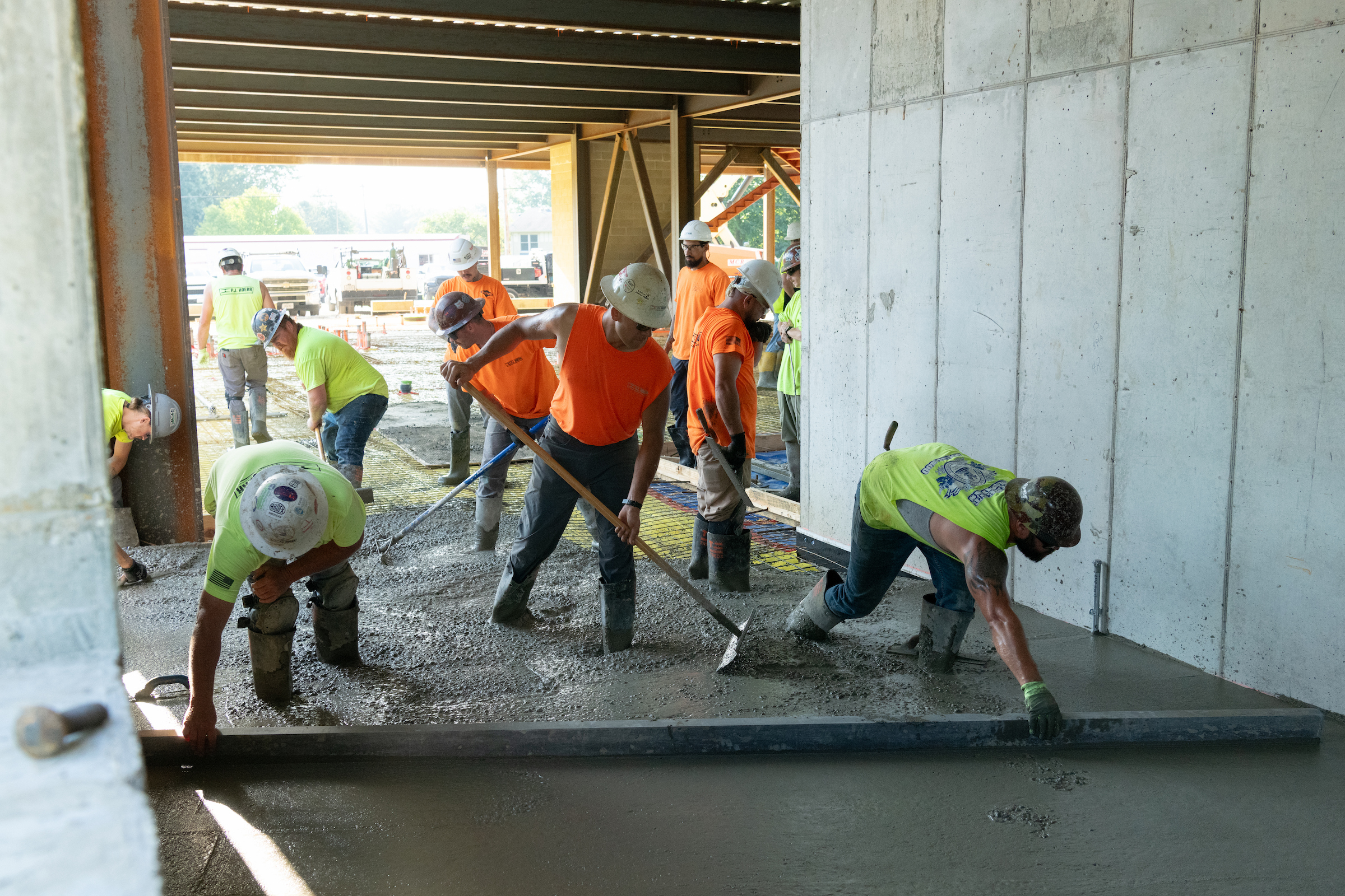Construction workers spread and level freshly poured concrete flooring inside the UIS Library Commons.