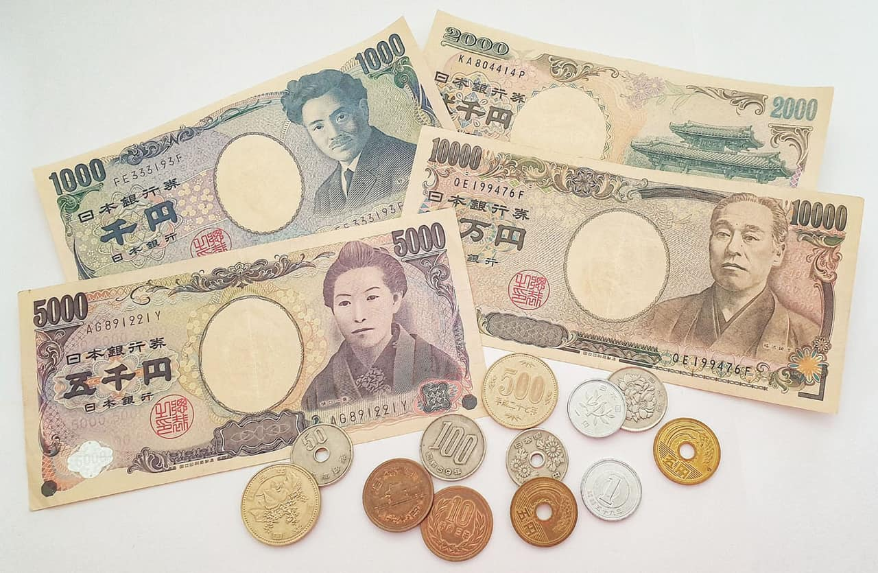 A collection of 4 bills and 12 multicolored coins representing the Japanese yen
