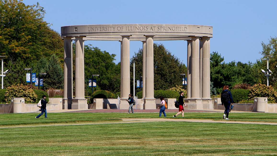 A photo of the UIS colonnade with students walking in front of it 