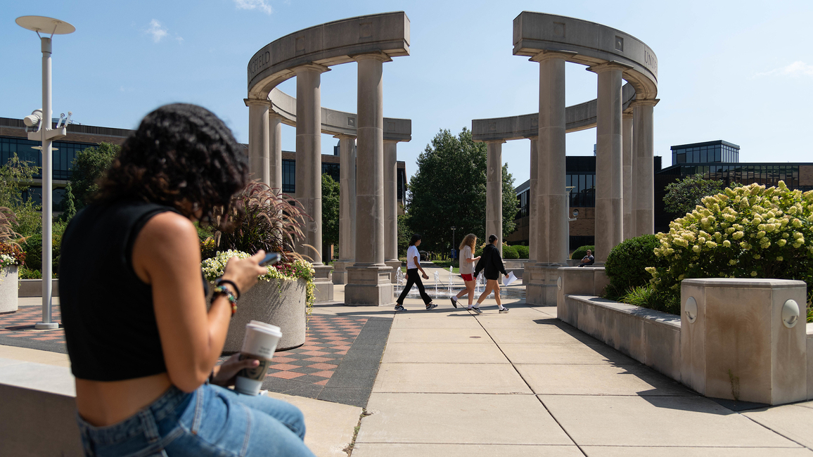 A student on their phone next to the colonnade 