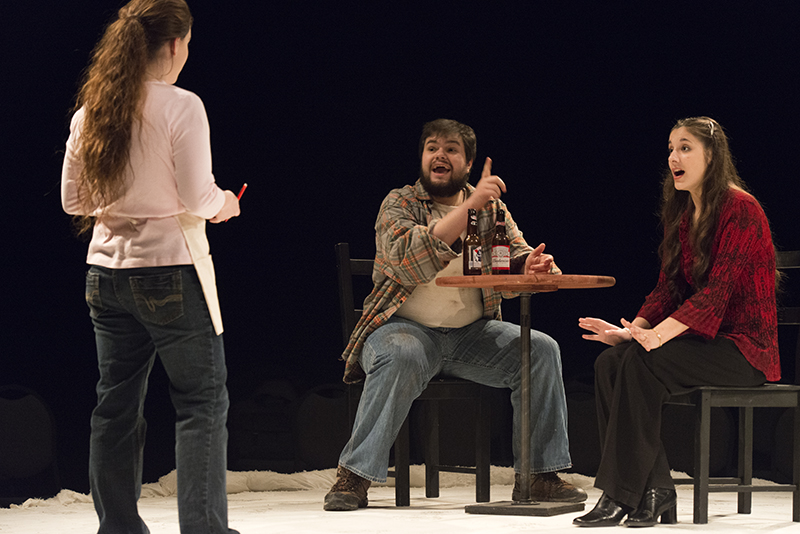 theatre students acting around a table during a production